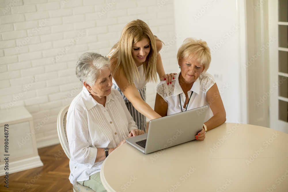 Happy women of three generations using laptop in the room at home Happy women of three generations using laptop in the room at home