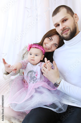 cheerful  young parents with their little daughter playing in the studio