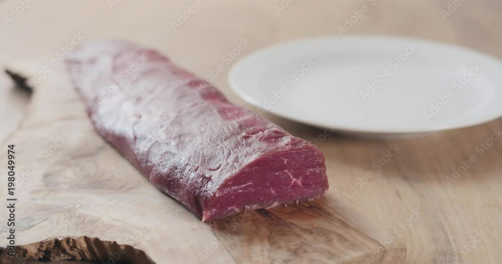 Slow motion slide raw beef fillet for steak on wooden board Slow motion slide raw beef fillet for steak on wooden board