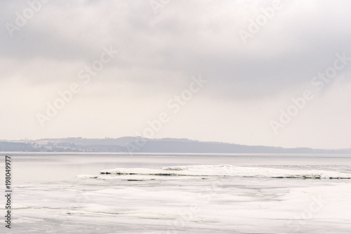 Ice on a lake in the winter with a misty landscape