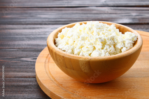 Home cottage cheese in a bowl on a wooden table.