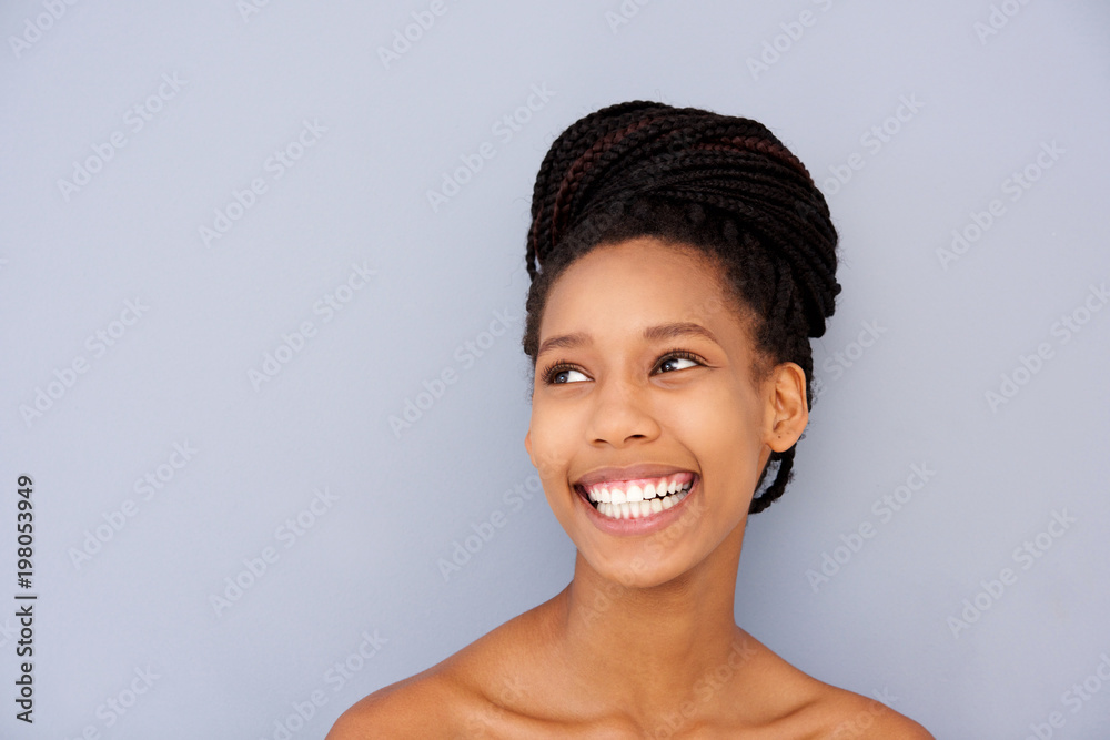 Close up young woman looking away and smiling against gray wall Close up young woman looking away and smiling against gray wall