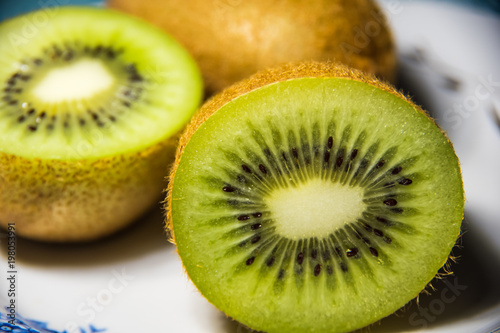 Kiwi cut in half and whole on a plate