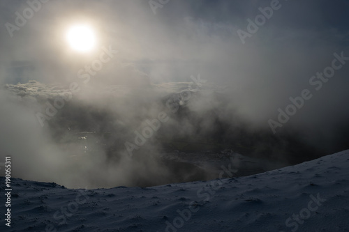 Foggy winters morning on snow capped hill in the sun