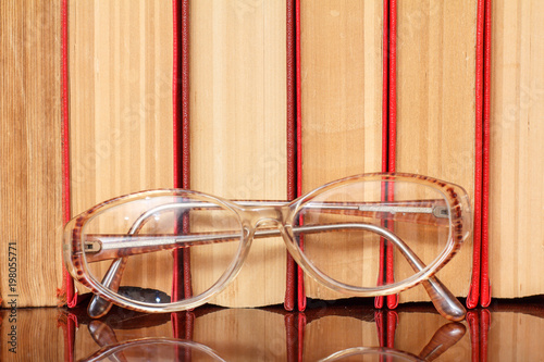 Glasses and many hardback books on wooden shelf