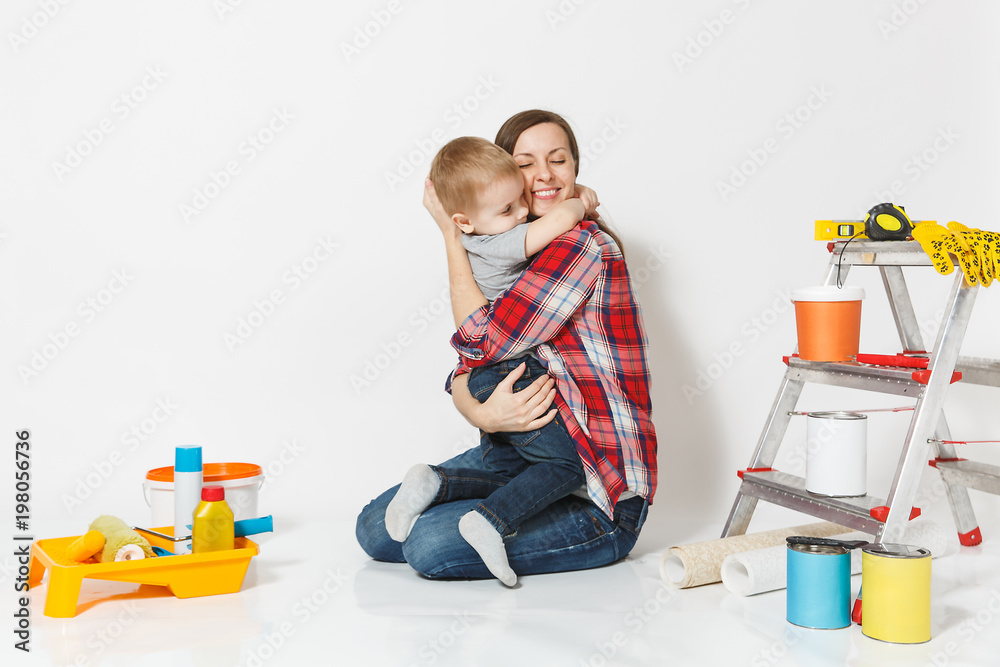 Mother hug her small son. Instruments for renovation apartment room isolated on white background. Wallpaper, gluing accessories, painting tools. Boy woman repairing home. Parenthood childhood concept. Mother hug her small son. Instruments for renovation apartment room isolated on white background. Wallpaper, gluing accessories, painting tools. Boy woman repairing home. Parenthood childhood concept.