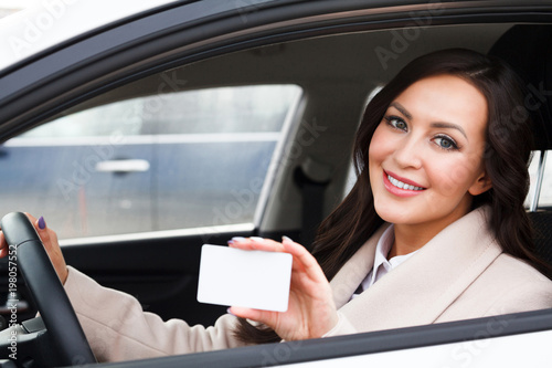 Portrait of smiling woman driver holding a white blank business card © Nobilior