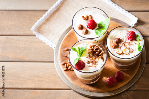 Dessert with berries, jelly, cream, nuts and mint leaf on a wooden cutting board