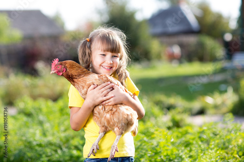 Child girl with hen in hands in rural