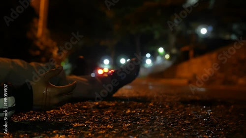 THE BODY OF A VIOLENCE VICTIM ON GROUND AT NIGHT, CAR PASSES photo