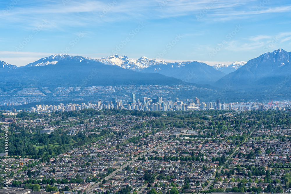 Aerial view of Vancouver downtown city in British Columbia with Snowcapped Mountaain and Clear Sky