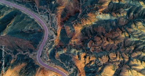 Aerial view on orange sandstone hills covered with sparse vegetation with curved, empty road creating a minimalistic landscape. Zhangye Danxia National Geopark, China. photo