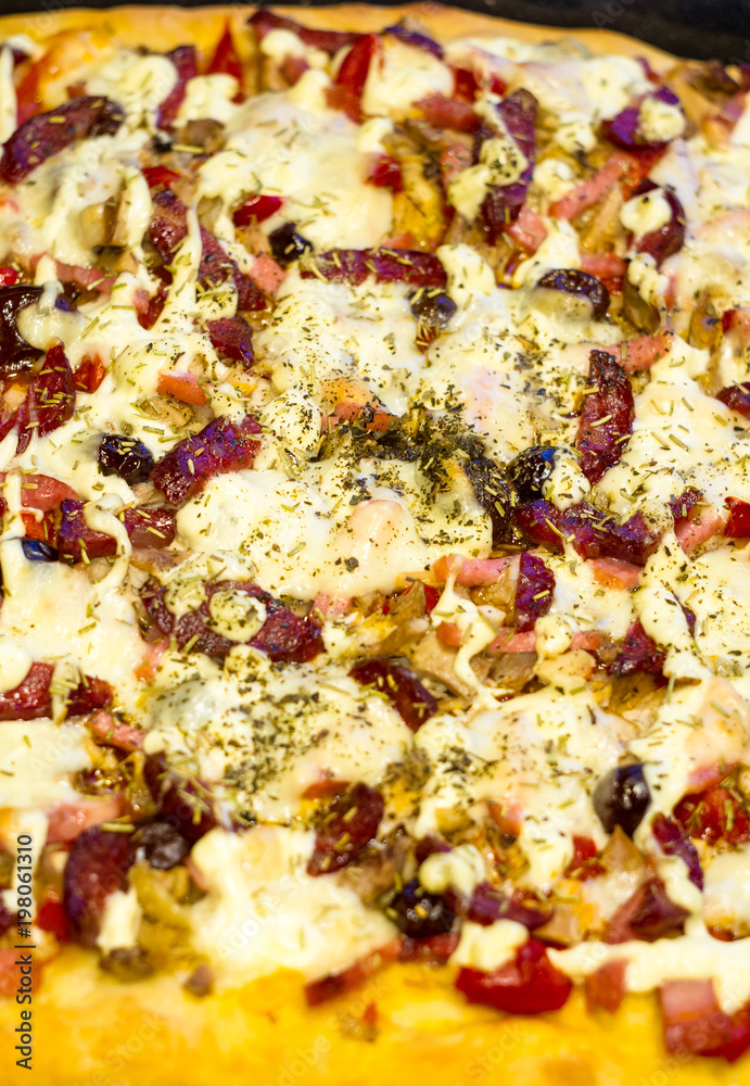 homemade pizza with peppers, plums, ham, sausage, cheese and spices, closeup