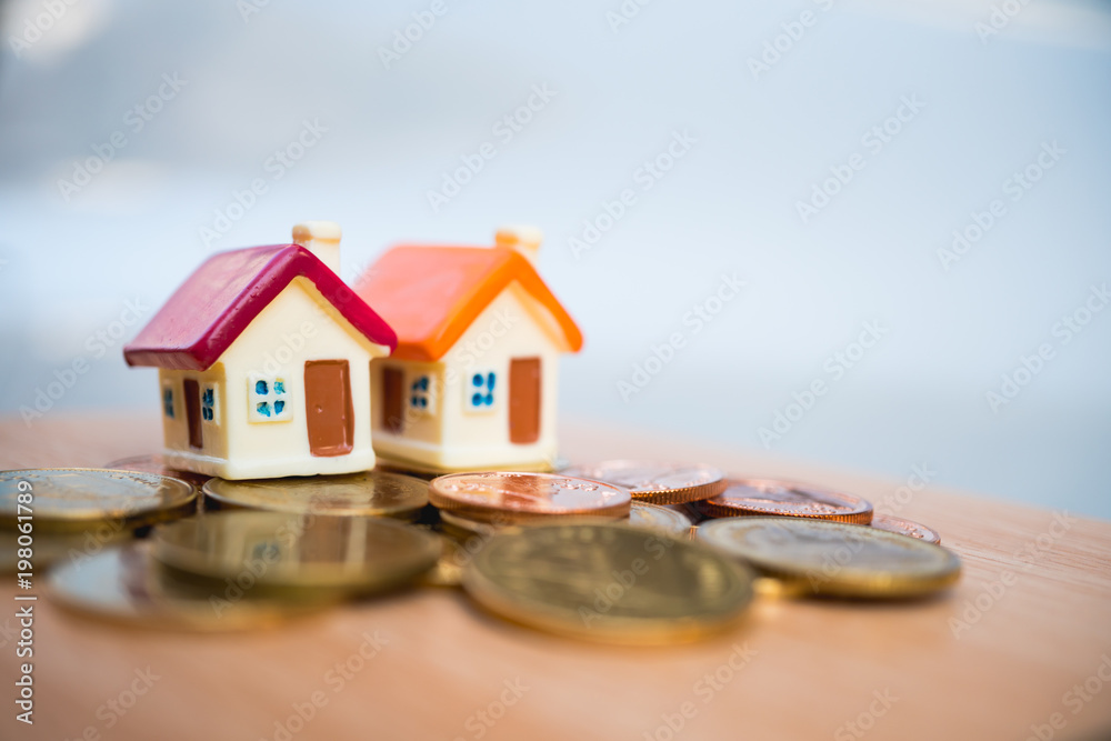 Miniature colorful couple house with stack coins on city background using as property and financial concept Miniature colorful couple house with stack coins on city background using as property and financial concept