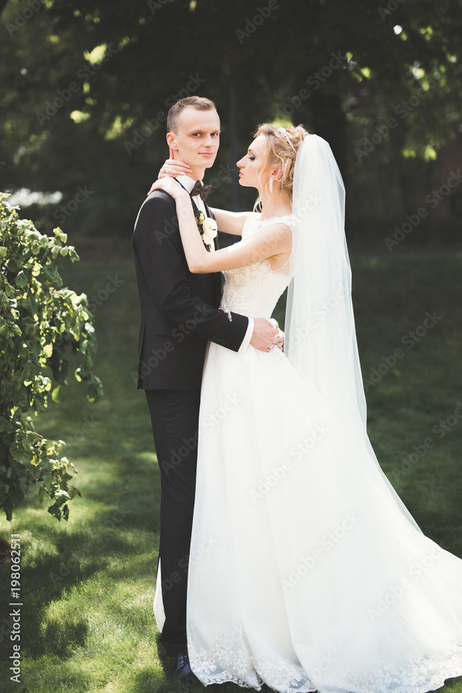 Lovely happy wedding couple, bride with long white dress posing in beautiful city