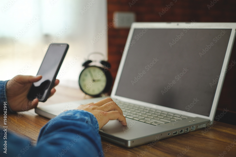a man holding mobile phone and working on computer for business a man holding mobile phone and working on computer for business