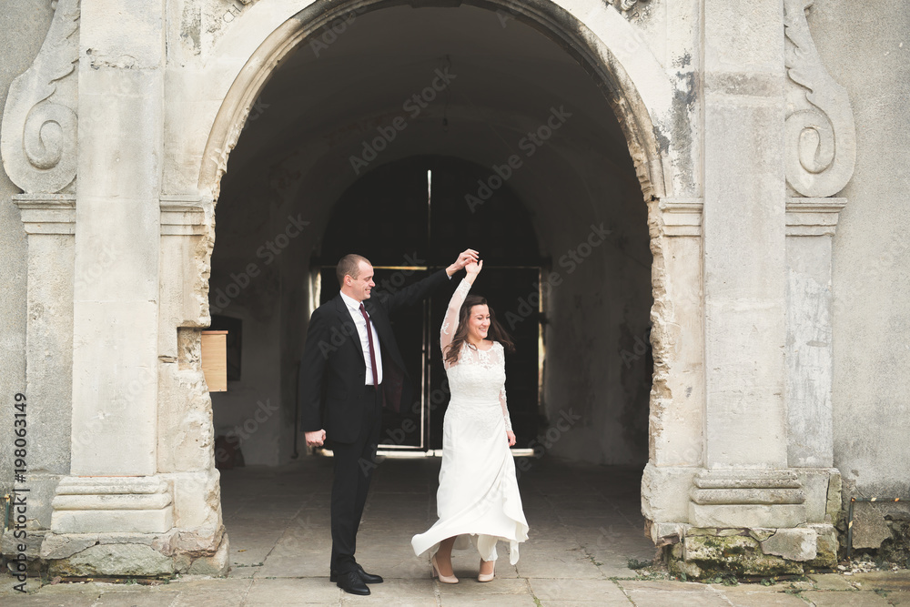 Beautiful fairytale newlywed couple hugging near old medieval castle