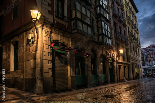 Narrow street corner with warm old lamp in the old city in Bilbao. Spain