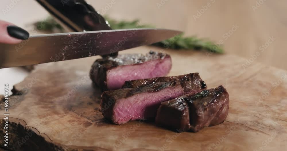 Slow motion slide slicing medium rare fillet mignon steak on wood board