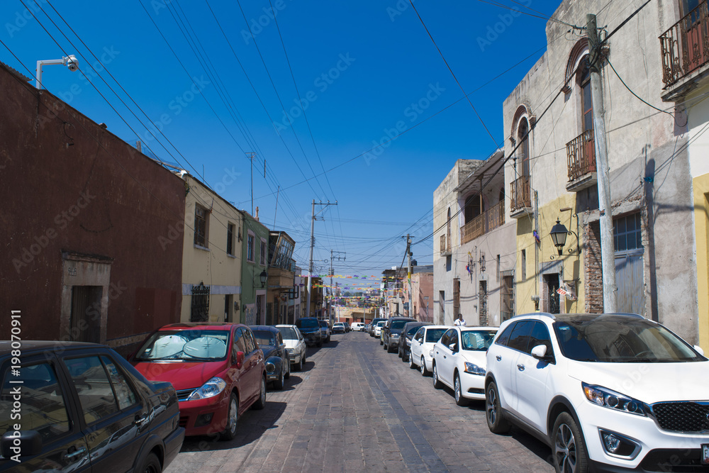 Succession of cars in street with cobblestone floor