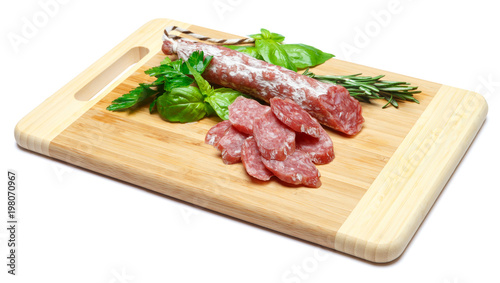 Dried sliced organic salami sausage on wooden cutting board