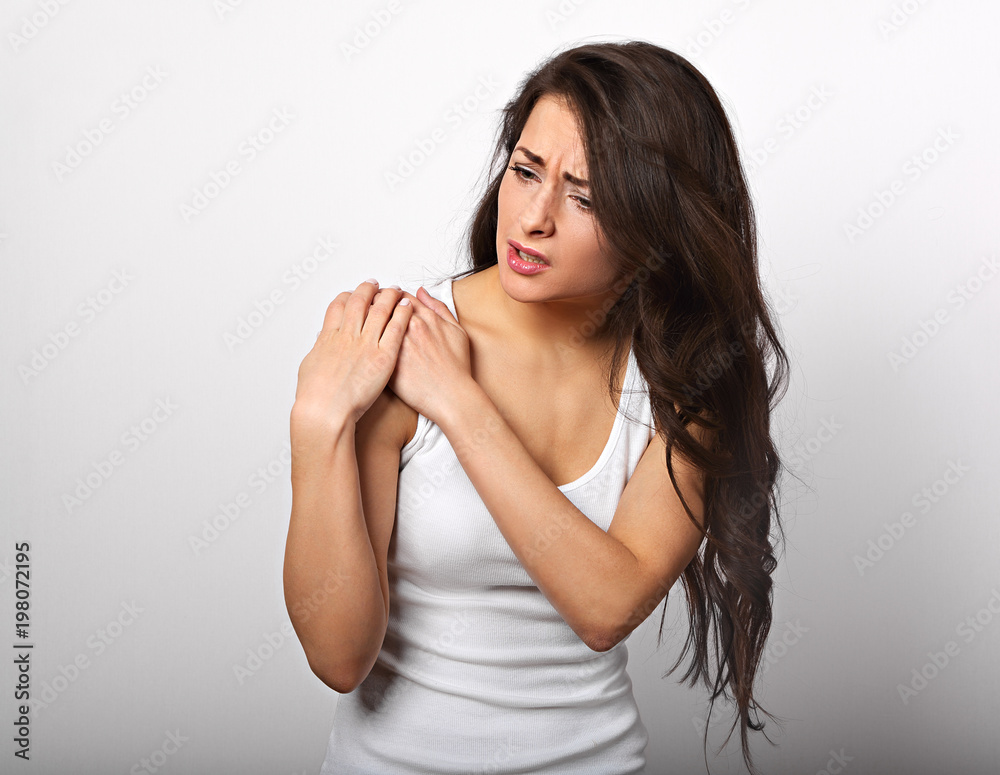 Casual beautiful woman with muscle pain in shoulder holding the hands with suffering face on white background Casual beautiful woman with muscle pain in shoulder holding the hands with suffering face on white background