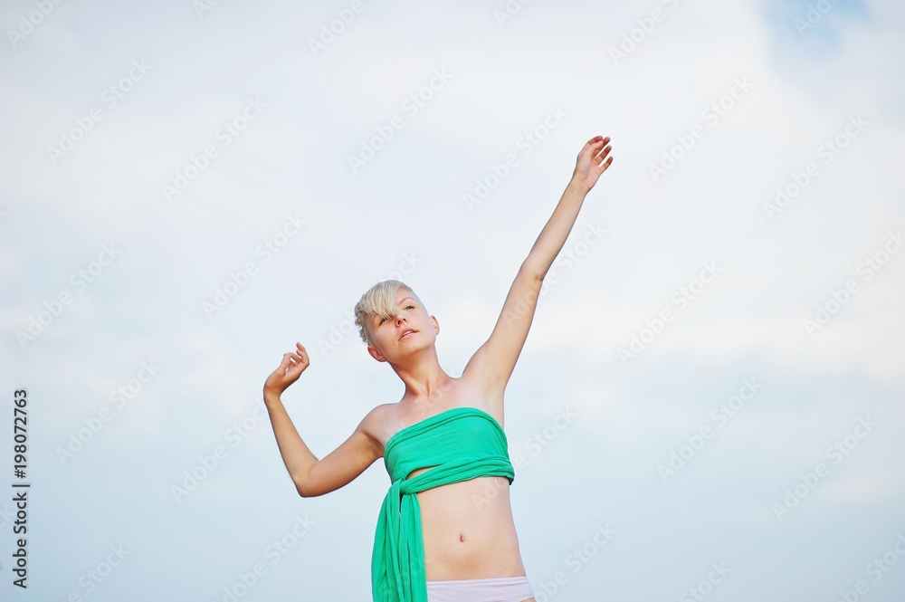 Side view of beautiful young blonde woman in swimsuit working out on the beach, doing yoga or pilates stretching exercise. Side view of beautiful young blonde woman in swimsuit working out on the beach, doing yoga or pilates stretching exercise.
