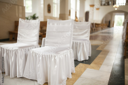 Atmosphere image of chairs decorated for marriage ceremony inside church
