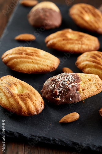 Freshly baked almond cookies on stone board over wooden background, top view, selective focus.