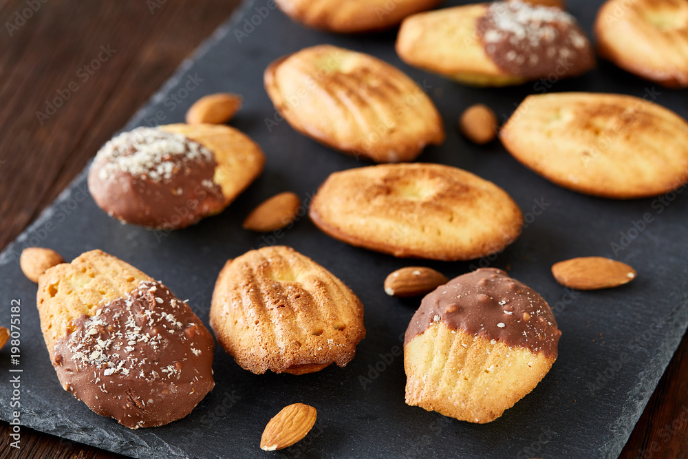 Freshly baked almond cookies on stone board over wooden background, top view, selective focus.