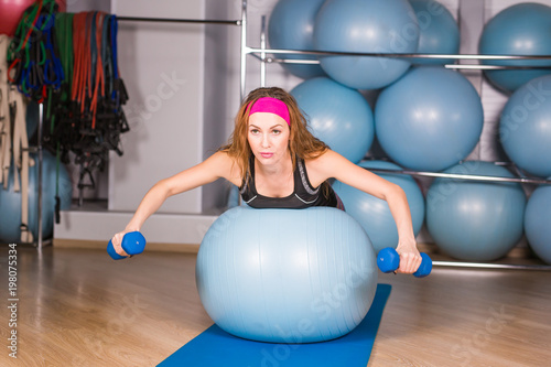 Woman exercising with dumbbells on a fitness ball