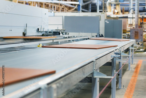 production  manufacture and woodworking industry concept - chipboards processing on conveyer at furniture factory workshop