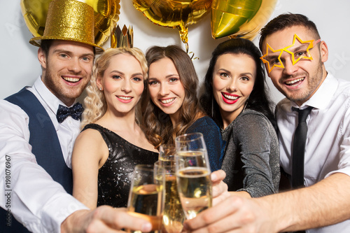 celebration, luxury and holidays concept - happy friends with golden party props clinking champagne glasses