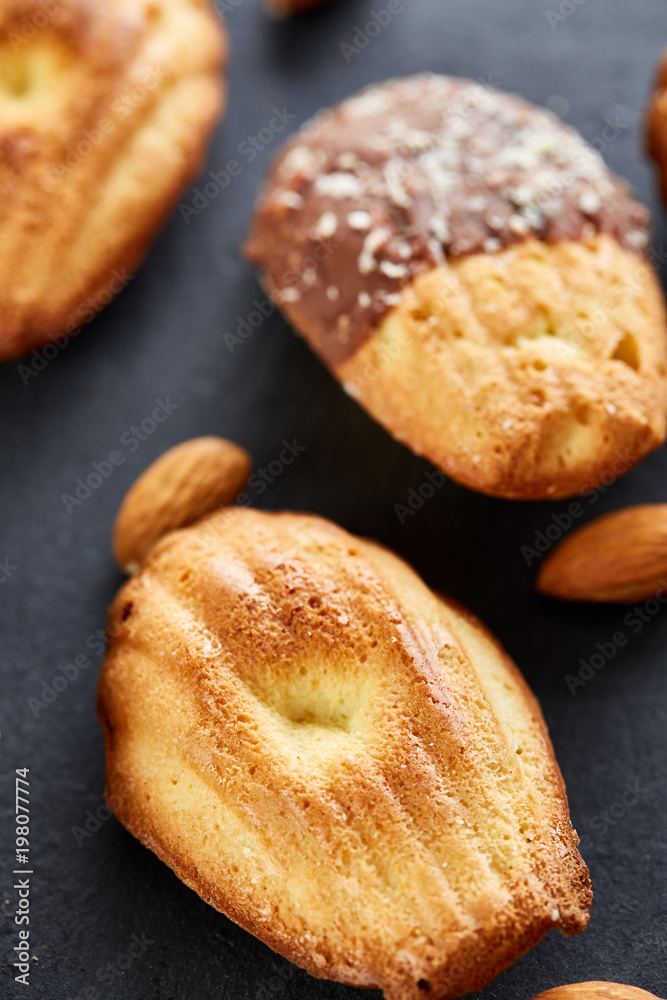 Freshly baked almond cookies on stone board over wooden background, top view, selective focus.