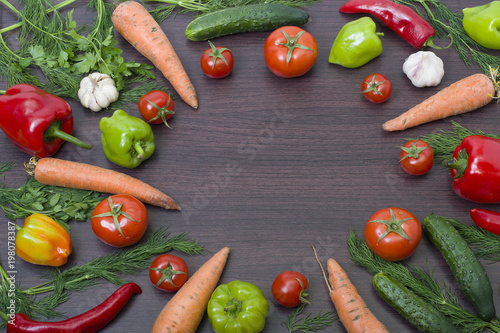 Vegetables concept on a wooden background. Carrots with green and red pepper on the table. Fresh vegetables on a brown wooden background.