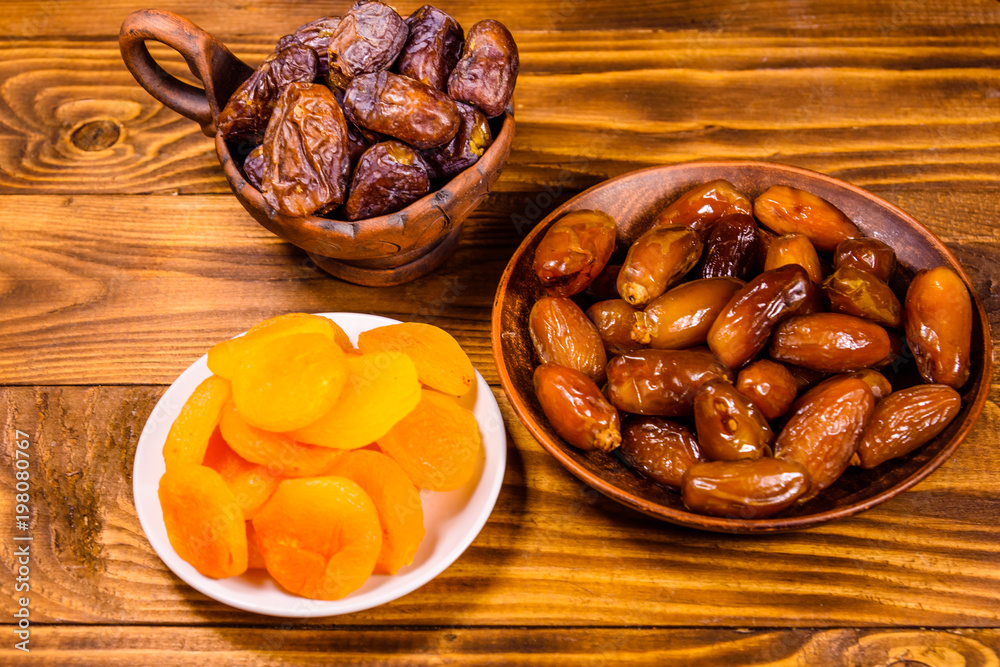 Date fruits and dried apricots on wooden table Date fruits and dried apricots on wooden table