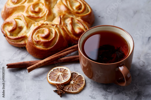 Homemade rose bread, cup of tea, dried citrus and spicies on white textured background, close-up, shallow depth of field