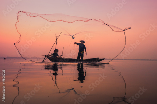 Fishermen using nets to catch fish at the Bangpra lake during sunrise time.