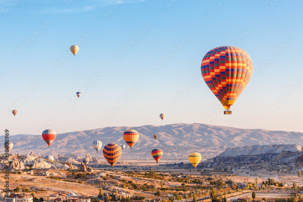 Obraz premium Many Hot air balloons flying over rocky landscape in Goreme city at Cappadocia, Turkey