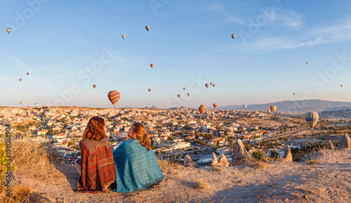 Couple of friends travelers enjoying valley view with wonderful balloons flight over Cappadocia valley in Turkey © EdNurg