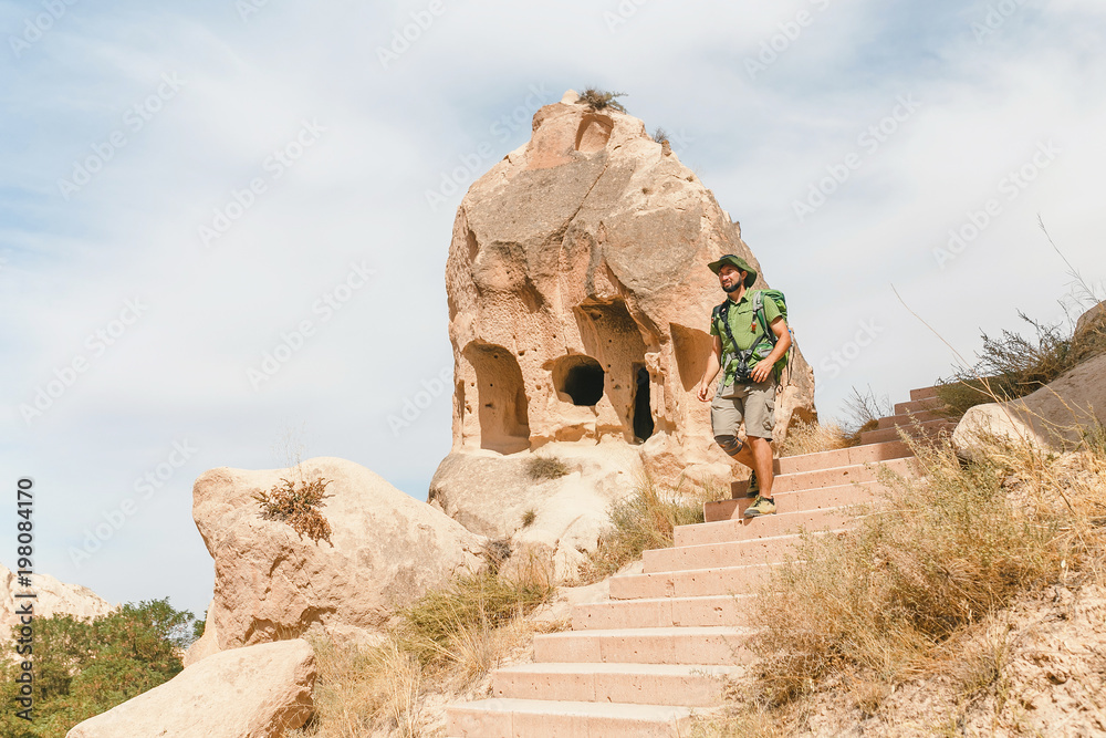 Young happy woman traveler alone hiking with backpack in the Rose valley of Cappadocia, Turkey