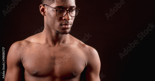 side view close up cropped portrait of strong nacked Afro male in glasses. clever sporsman photo