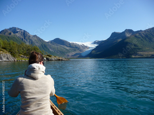 Woman paddling to Engabreen, Svartisen glacier over Holandsfjord in Norway