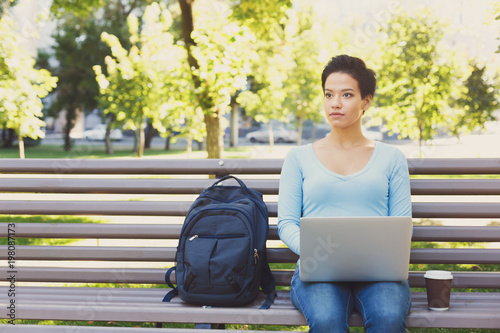 Young woman typing on laptop sitting outdoors