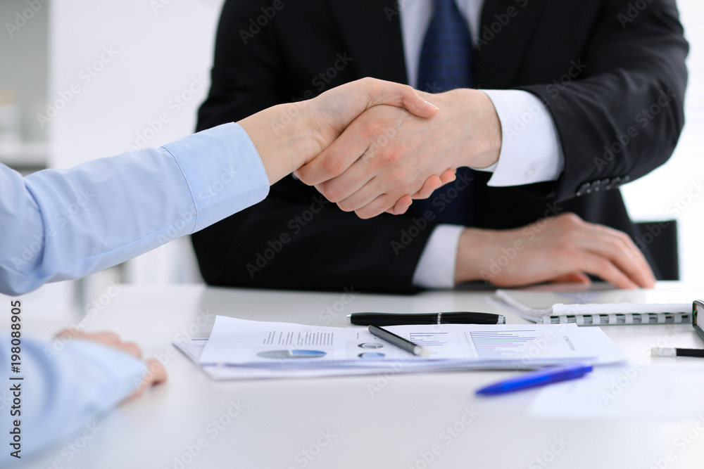 Close Up of unknown business people shaking hands while finishing up a meeting. Handshaking, agreement or success concept in people communication Close Up of unknown business people shaking hands while finishing up a meeting. Handshaking, agreement or success concept in people communication