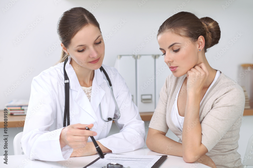 Doctor and patient sitting at the desk. The physician or therapist makes a diagnosis. Health care, medicine and patient service concept Doctor and patient sitting at the desk. The physician or therapist makes a diagnosis. Health care, medicine and patient service concept