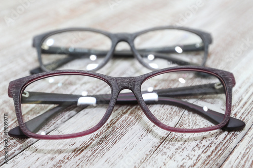 Two pairs of stylish women's eyeglass frames on white wooden background