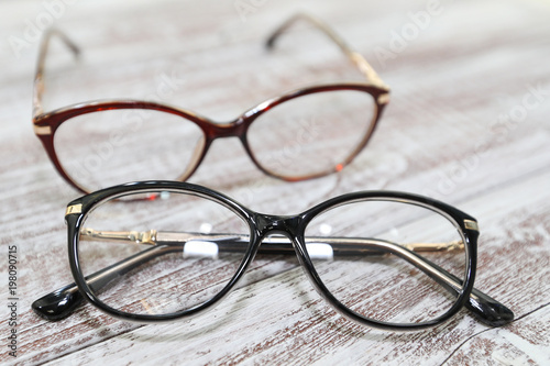 Two pairs of stylish women's eyeglass frames on white wooden background