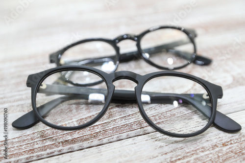 Two pairs of fashionable men's eyeglass frames on white wooden background