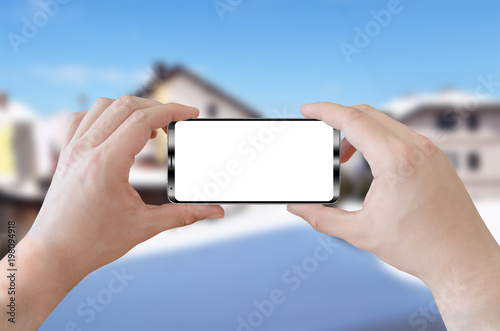 Man holding smart phone device with isolated white screen for mock up. Horizontal position